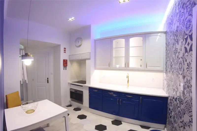 Vista geral da cozinha com mesa branca, cesto dourado e chão hexagonal preto e branco