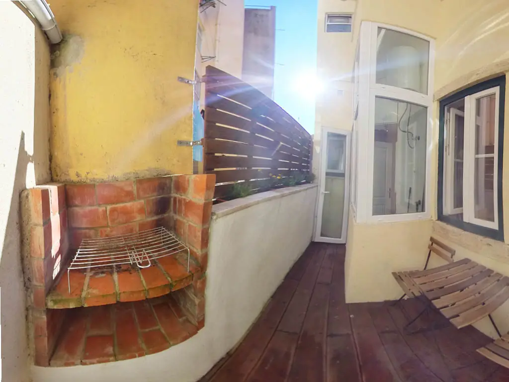 Pátio privado com deck de madeira, churrasqueira em tijolo e mesa para dois