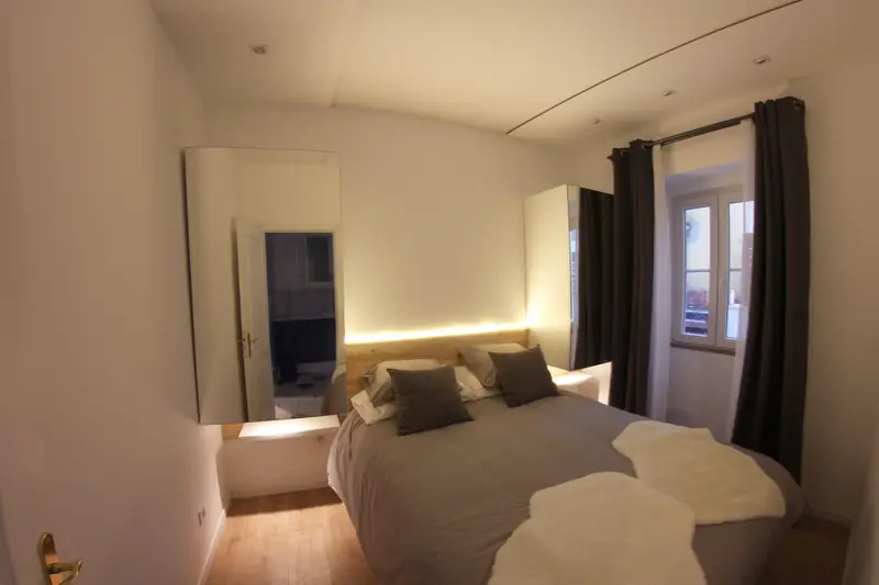 Quarto Sereno com cabeceira em madeira natural iluminada e cortinas cinza